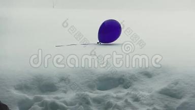 飘浮在雪地上的一个飘零的紫色气球